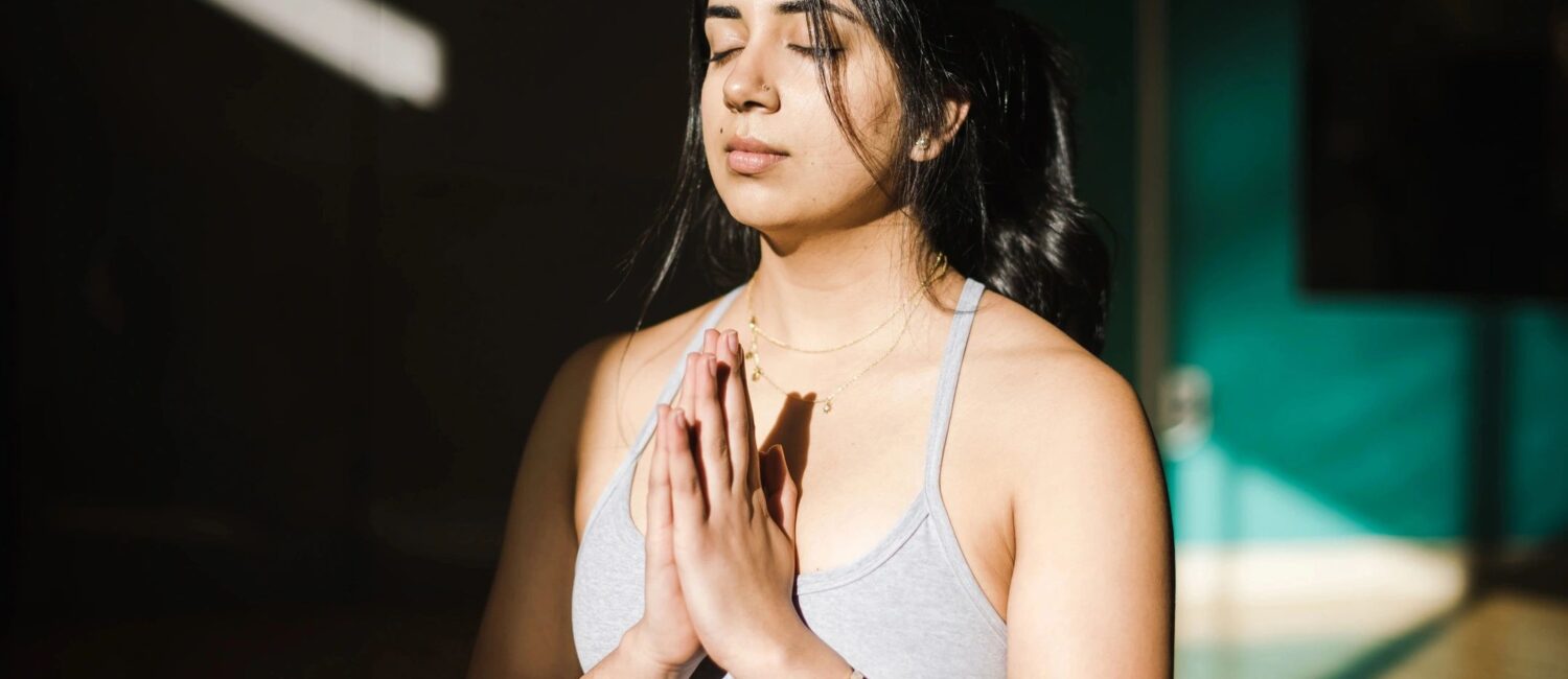 Young woman in prayer pose during yoga class.