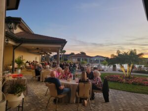 people seated at tables on a veranda at sunset